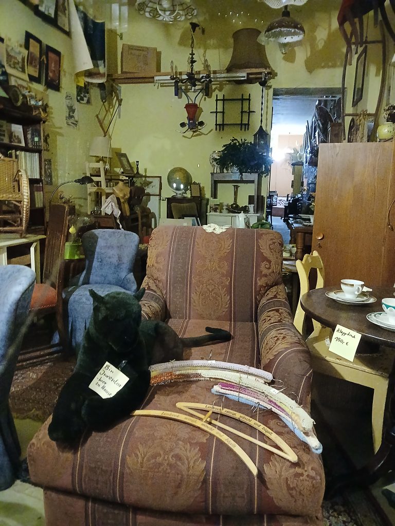 The interior of an antiques dealer in Berlin. It holds a variety of old furniture and knick-knack. Most prominently a stuffed panther with a sign around his neck that reads in German "I am inventory - I live here" Photo taken by Angela Kipp