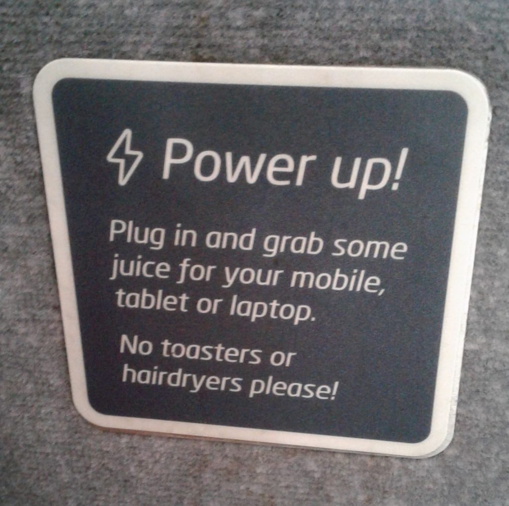 Photo taken on a British train: “Power up! Plug in and grab some juice for your mobile, tablet or laptop. No toasters or hairdryers, please!”